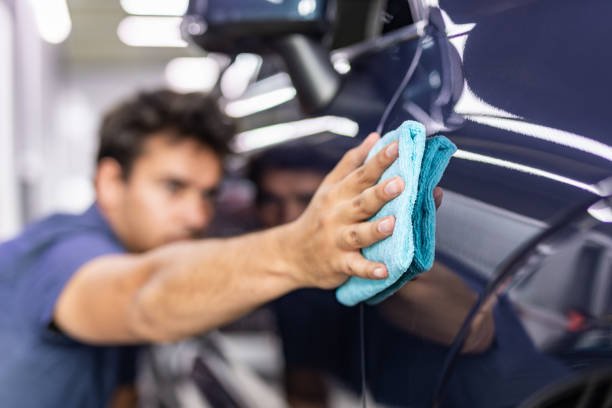 Car detailing - the man holds the microfiber in hand and polishes the car. Selective focus.